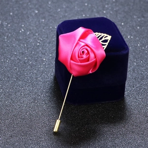 Detail of pink satin rose brooch with gold pin on dark velvet jewelry display