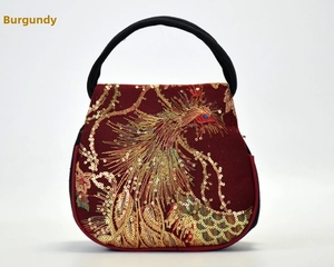 Detail of wine red ethnic handbag featuring golden phoenix embroidery and sequins