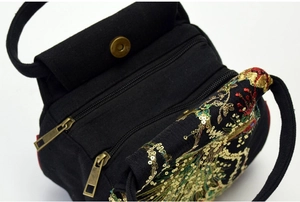 Close-up of dual zipper compartments and peacock embroidery on black ethnic handbag