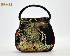 Macro view of ethnic handbag with peacock embroidery and sparkling gold sequins
