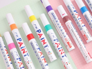 Diagonal arrangement of multi-colored GANA SP110 oil-based paint markers on grid paper
