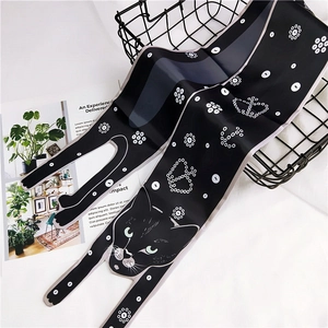 Detail view of a black cat patterned silk scarf with white polka dots on a metal basket