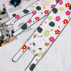 Detailed view of a white silk scarf featuring red flowers and a cute cat illustration