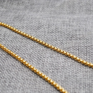 Detailed macro view of golden stainless steel ball chain with metallic luster finish