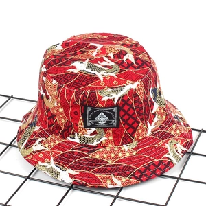 Detail of red bucket hat with Japanese koi fish pattern and embroidery on black metal grid