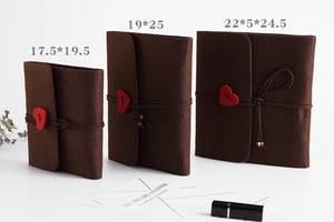 Detailed view of three sizes of brown felt scrapbooks with red heart closures and strings