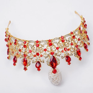 Macro shot of gold baroque crown with red gemstones and white woven pendant detail