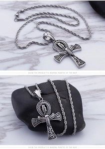 Detail view of silver stainless steel Ankh cross necklace on marble and stone background