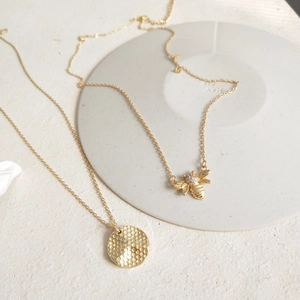 Detail of 925 silver gold bee pendant with rhinestones and textured round disc necklace