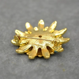 Detailed back view of a golden flower brooch showing the secure safety pin fastener