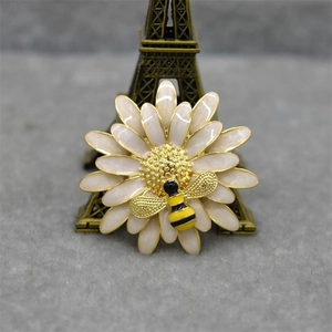 Macro detail of enamel daisy flower brooch with yellow honeybee and golden finish