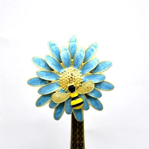 Detailed blue daisy enamel brooch featuring a small gold and black bee on an Eiffel stand