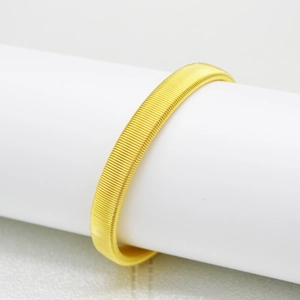 Detailed view of a men's golden metal spring bracelet displayed on a white stand