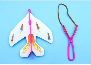 Flat lay of a foam glider toy with rocket stickers and pink launcher on blue background