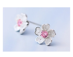 Macro shot of silver cherry blossom earrings with matte petals and pink zircon centers