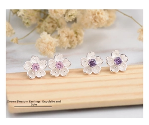 Detailed view of silver cherry blossom studs with pink and purple center gemstones