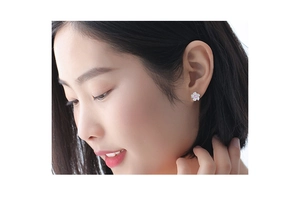 Close-up of pink cherry blossom earrings featuring a crystal center on a model's ear