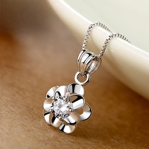 Macro shot of silver rose pendant with a sparkling zircon center on a thin box chain