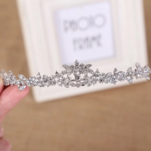 Detailed close-up of a silver bridal crown with intricate floral patterns and shiny rhinestones