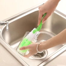 Deep cleaning long handle brush scrubbing a transparent glass in a kitchen sink