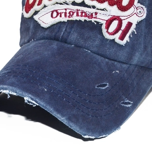Macro shot of distressed brim and 3D embroidery on washed denim baseball cap