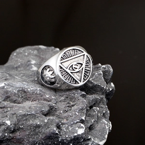 Detail of vintage silver All-Seeing Eye ring on dark rock with intricate metal textures