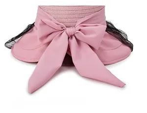 Detail of pink straw sun hat with large bow and lace mesh fabric texture