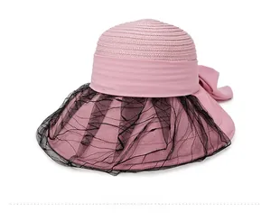 Detail of pink woven sun hat featuring elegant black polka dot lace veil and large bow