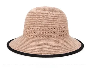 Dettaglio del cappello da spiaggia intrecciato traspirante con motivi traforati e bordo nero
