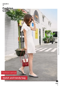 Detail of red and cream crossbody bag featuring a golden deer charm on a street model