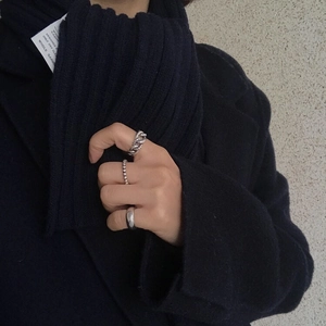 Detail of stacked 925 silver rings including chain and bead styles worn by a model