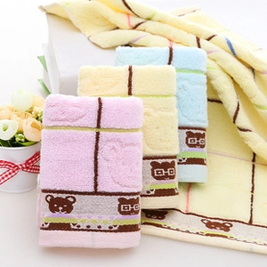 Détail de serviettes en coton doux avec motifs d'ours en rose jaune et bleu