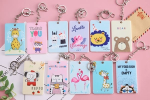 Close-up of colorful cartoon animal card holders with metal keychains on a pink background