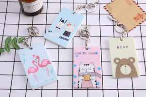 Detailed view of pastel cartoon card holders and metal keychains on a checkered surface
