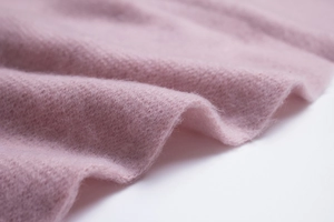 Close-up of soft light pink knitted scarf fabric with warm long fluffy wool texture