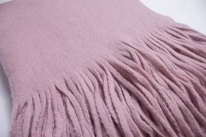 Detailed macro view of soft pink wool-like scarf texture with long fringe tassels