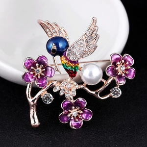Detail of hummingbird brooch with colorful enamel, rhinestones and pearl on floral branch