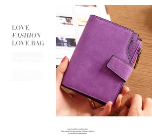 Close-up of purple matte leather short wallet with snap button and zipper on a wooden table