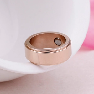 Rose gold magnetic therapy titanium steel ring resting on a white ceramic edge