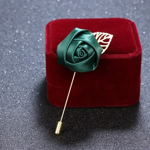 Detailed view of green satin rose brooch with gold metal stem on a velvet box