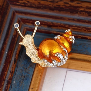 Macro detail of golden snail brooch with amber shell and sparkling white rhinestones
