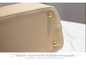 Close-up of beige leather bucket bag base with protective gold metal studs and neat stitching