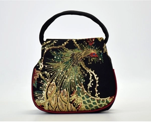 Detail of peacock embroidery on a black ethnic silk handbag with gold sequins and red trim