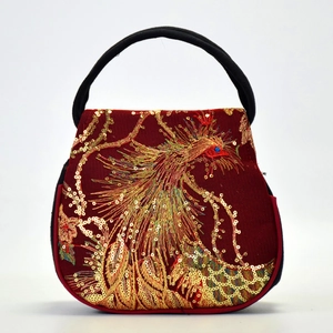 Ethnic red embroidered handbag featuring golden peacock patterns and black handles