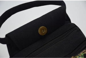 Detailed macro of black cotton canvas texture with bronze magnetic buckle and zipper