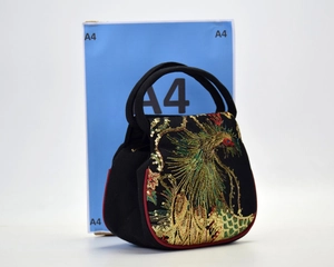 Detailed peacock embroidery on a black handbag with size comparison next to A4 box