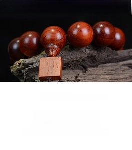 Macro detail of polished rosewood prayer beads with natural grain texture and wooden pendant