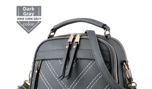 Detail view of dark gray pebble leather bag with white V-stitching and reinforced handle