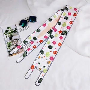 Flat lay of a cartoon cat print long silk scarf with sunglasses and a floral card