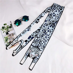 Detail of long silk scarf with blue leopard print and leopard head patterns on white fabric